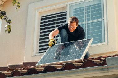 Man with Gloves Holding Solar Panels on the Roof